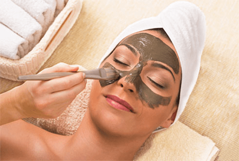 A brush-applied facial mask application in a serene setting.